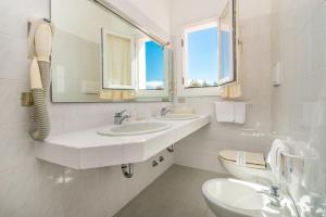 Baño blanco con 2 lavabos y espejo en Hotel 3 Botti en Baja Sardinia