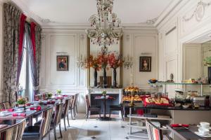 a dining room with tables and chairs and a chandelier at Hôtel Regent's Garden - Astotel in Paris
