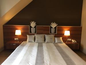um quarto com uma grande cama branca e 2 candeeiros em Alfa Hotel em Gyor