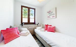 two beds in a room with red and white pillows at Apartamenty EverySky Nadrzeczna 3E-3D in Karpacz
