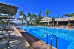a large swimming pool with chairs and palm trees at Mahogany Hotel Residence & Spa in Le Gosier