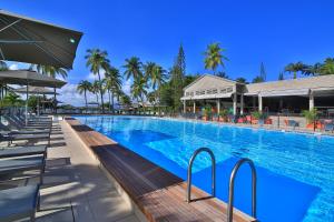 una grande piscina con sedie e palme di Mahogany Hotel Residence & Spa a Le Gosier