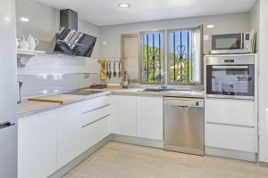 una cocina con armarios blancos y electrodomésticos de acero inoxidable en Villa Maria Portals Nous, by Priority, en Portals Nous