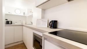 una cocina con armarios blancos y un aparato negro en Italianway-San Maurilio 20 studio en Milán