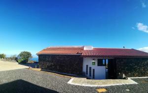 een klein huis met een rood dak bij La Casa del Risco in El Pinar del Hierro