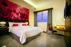 um quarto com uma cama grande e uma pintura vermelha em favehotel Kusumanegara em Yogyakarta