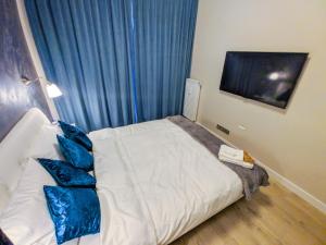 une chambre avec un lit blanc avec des oreillers bleus dans l'établissement Verde Apartament, à Zielona Góra