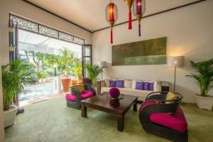 uma sala de estar com um sofá, uma mesa e cadeiras em The Apsara em Luang Prabang