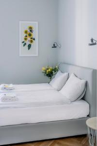 a white bed with a vase of flowers on it at APARTEL Plac Unii Lubelskiej Studio in Warsaw