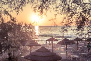 a beach with umbrellas and the ocean at sunset at Grand Hotel Costa Brada in Gallipoli