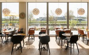 a restaurant with tables and chairs and a large window at ibis Styles Versailles Guyancourt in Guyancourt