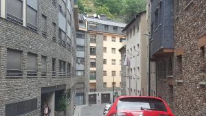 a red car parked on a street between buildings at Valls Rent in Andorra la Vella