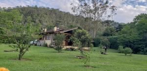 a house in the middle of a field with trees at Vale do Alcantilado in Visconde De Maua