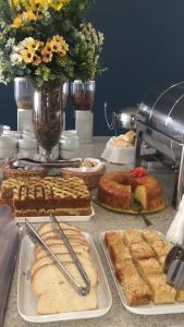 uma mesa com diferentes tipos de bolos e pastelarias em Villa Premium Hotel em Erechim