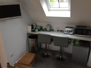 a kitchen with a counter with two chairs and a microwave at Oliver's Studio at Oliver's Yard in Shipton under Wychwood