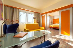 ブルノにあるホテル コンチネンタルのテーブル、椅子、ベッドが備わる客室です。