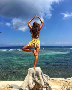a young girl is standing on a rock on the beach at Twilight Ceningan in Nusa Lembongan