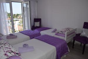a room with three beds with purple sheets and a balcony at Villa Zorana hostel in Hvar