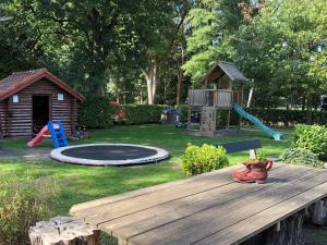 um parque infantil com uma mesa de madeira e um trampolim em Boomgalows De Roestelberg em Kaatsheuvel