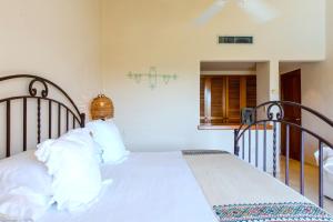 une chambre avec un lit avec des draps blancs et des oreillers dans l'établissement Rosa Del Desierto | 3BR | Condo | Puerto Aventuras, à Puerto Aventuras