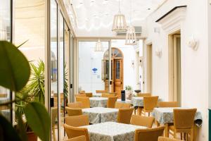 a restaurant with white tables and chairs and plants at Hotel Del Corso in Sorrento