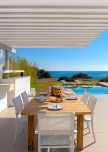 a wooden table and chairs in a patio with a pool at Albatross Beach Front Villas in Gennadi