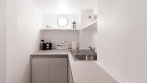 a white kitchen with a sink and a counter at Italianway-San Maurilio 20 studio in Milan