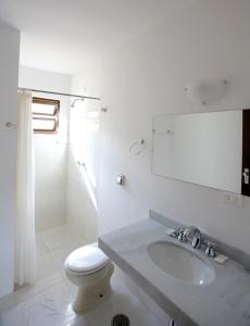 a white bathroom with a toilet and a sink at Residencial Vilamar in Ilhabela +41 photos