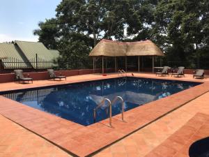 a swimming pool with chairs and a gazebo at Governors Club in Entebbe