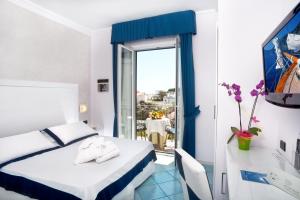 a hotel room with a bed and a desk and a window at Hotel Villa Durrueli Resort & Spa in Ischia