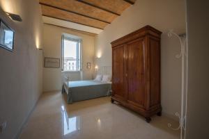 sypialnia z łóżkiem i drewnianą szafką w obiekcie La Residenza in Piazza Grande w mieście Foligno