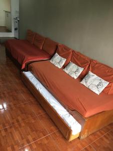 a brown couch with four pillows on a wooden floor at Rincón de Araus in Colonia del Sacramento