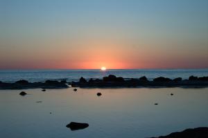 una puesta de sol sobre el océano con rocas en el agua en A due passi dal mare en Realmonte