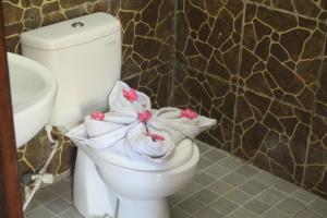 a bathroom with a toilet with towels and a sink at Ombak Homestay in Gili Trawangan
