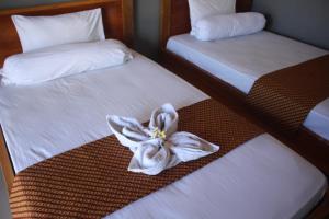 dos camas con sábanas blancas con una flor. en Ombak Homestay, en Gili Trawangan