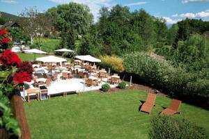 eine Gruppe von Tischen und Stühlen in einem Garten in der Unterkunft Hotel Kärnten in Krumpendorf am Wörthersee