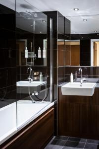 a bathroom with two sinks and a glass shower at Aparthotel Adagio London Brentford in Brentford