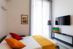 a bedroom with a bed with orange pillows and a flat screen tv at Acate81 Lifestyle Apartment in Naples