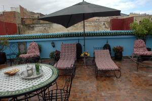 een patio met een tafel en stoelen en een parasol bij Riad Lahboul in Meknès