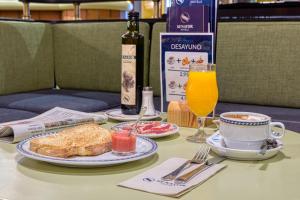 una mesa con un plato de tostadas y una taza de zumo de naranja en Senator Huelva, en Huelva