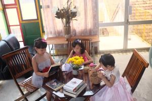 three girls sitting at a table with a laptop at Trại Hoa Vàng Homestay at Phú Yên in Ðông Tác (1) +91 photos