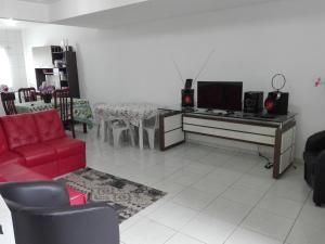 a living room with a red couch and a television at Casa de Praia in Itapema