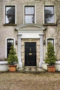 une maison avec une porte noire et deux plantes dans l'établissement Rathaspeck Manor B&B, à Wexford