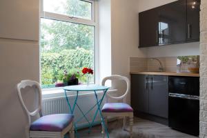 cocina con mesa, sillas y ventana en The Retreat at Plover Cottage Lindley en Huddersfield