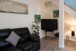 - un salon avec un canapé en cuir noir et une télévision à écran plat dans l'établissement The Retreat at Plover Cottage Lindley, à Huddersfield