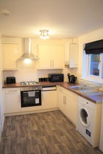 a kitchen with white cabinets and a washing machine at Kelpies Serviced Apartments-McKay in Falkirk