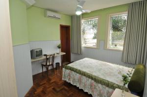 um quarto com uma cama, uma secretária e uma televisão em Hotel Ivo De Conto em Porto Alegre
