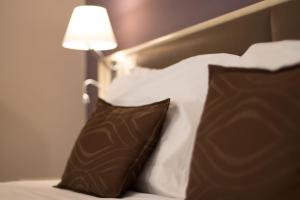 a bed with two brown and white pillows and a lamp at Hotel Soleluna in Piano di Sorrento