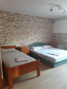 a bedroom with two beds and a brick wall at Otok Krk Apartments in Čižići