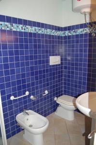 a blue tiled bathroom with a toilet and a sink at monolocale 2 Planasia in Cavo